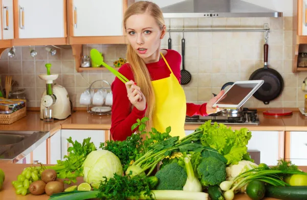 Young woman in kitchen having many green vegetables on table, holding tablet thinking about cooking something and searching for recipes in internet. Woman having green vegetables thinking about cooking,Image: 1121011550, License: Royalty-free, Restrictions:, Model Release: no, Credit line: -/Ingram/Profimedia